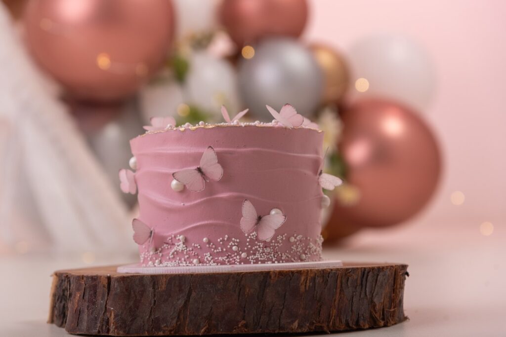 Espectacular torta decorada en crema rosada adornada con mariposas en impresión comestible. Esta impresionante foto en primer plano captura la delicadeza y belleza de la crema rosada, complementada perfectamente por las vibrantes mariposas comestibles. Las mariposas, elaboradas con detalles realistas, parecen estar listas para alzar vuelo, añadiendo un toque mágico y encantador a la torta. Ideal para celebraciones especiales, esta torta es una verdadera obra de arte que combina sabor y estética de manera sublime.