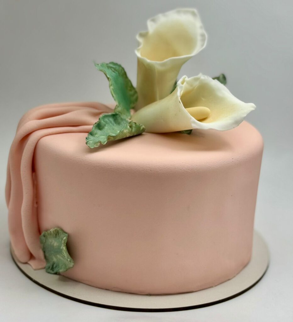 Deslumbrante torta personalizada de decorada en fondant con una linda flor blanca en la parte superior Disponible en Bogotá