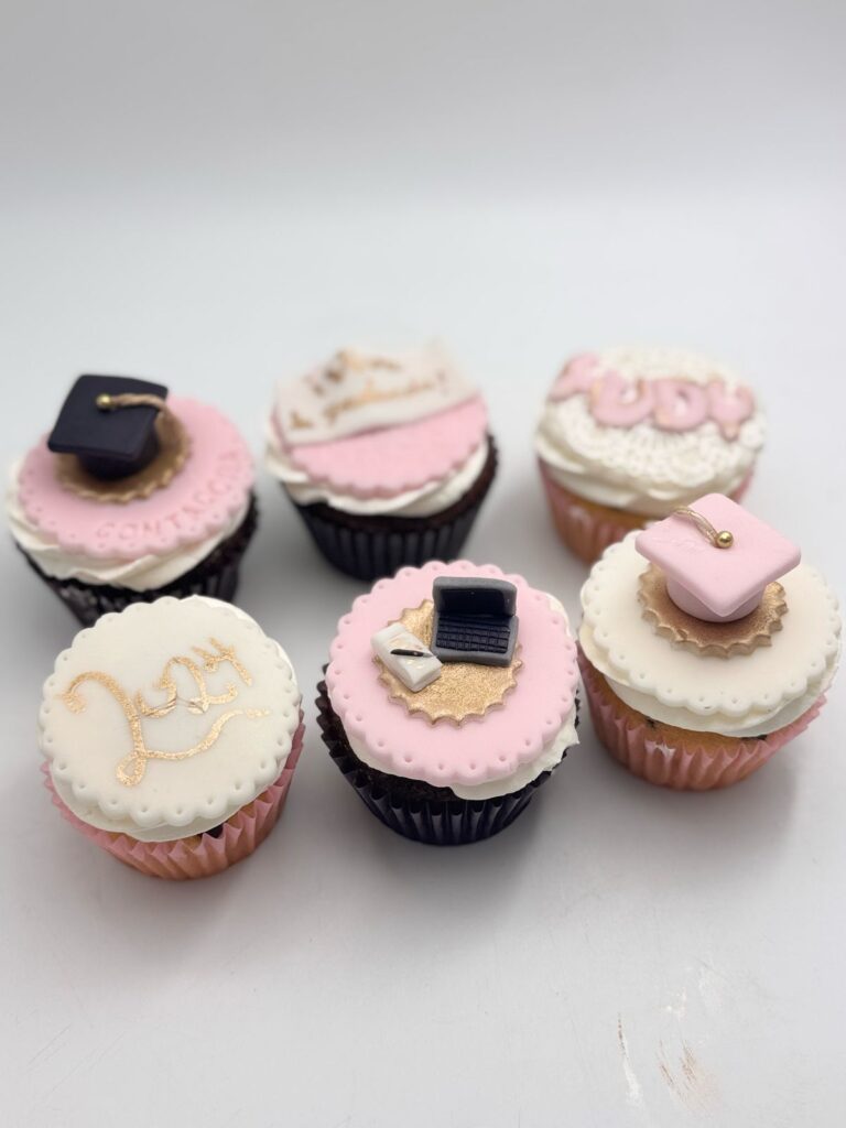 Cupcakes personalizados en Bogotá para graduación, decorados en rosa y blanco con birrete, diploma y mensajes festivos