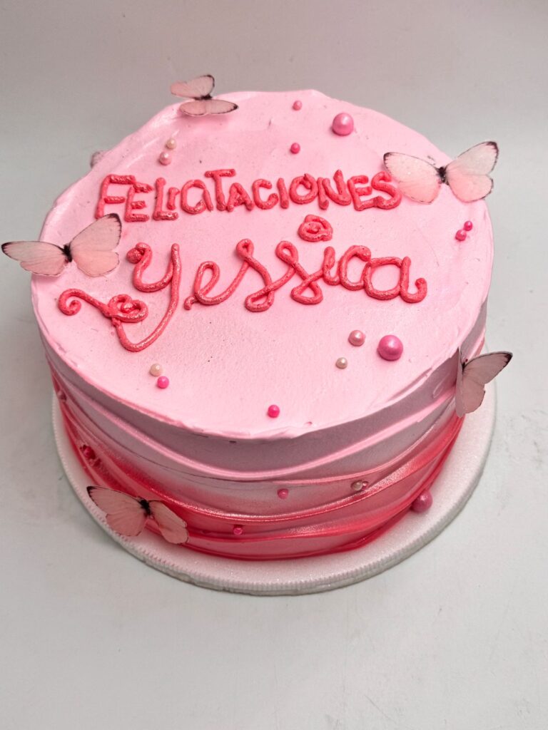 "Torta decorada en crema rosa con mariposas comestibles, perlas y mensaje personalizado de felicitación para Yessica, diseño femenino y delicado ideal para celebraciones especiales"