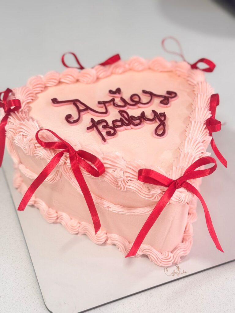 "Pastel de corazón personalizado para baby shower o cumpleaños. Diseño único con escritura 'Aries Baby' y detalles en rojo. Perfecto para celebrar la llegada de un bebé Aries."