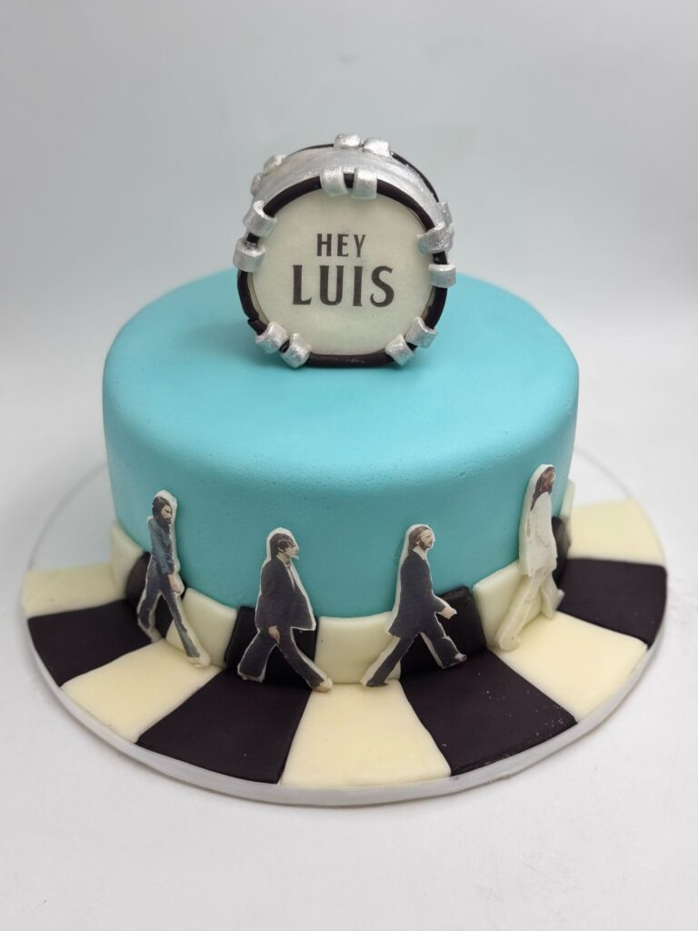 Torta personalizada temática The Beatles – Abbey Road 🎸
Celebra con estilo con esta original torta personalizada inspirada en The Beatles, perfecta para fanáticos de la música y los clásicos del rock. Decorada en tonos celestes con un acabado liso de fondant, esta torta destaca por su diseño creativo que recrea la icónica portada de Abbey Road con figuras comestibles de los integrantes de la banda cruzando la calle. El toque final lo da un tambor personalizado en la parte superior con el mensaje “Hey Luis”, ideal para cumpleaños o celebraciones temáticas.Esta torta es un excelente ejemplo de nuestras tortas personalizadas para adultos, ideal para quienes buscan una torta temática musical, tortas para fanáticos de The Beatles o diseños únicos y creativos. Elaborada con materiales de la mejor calidad, sabor inigualable y una decoración hecha a mano.✨ Ofrecemos tortas por encargo en Bogotá y envíos a domicilio. ¡Haz de tu evento algo inolvidable con nuestras tortas personalizadas con temática especial!