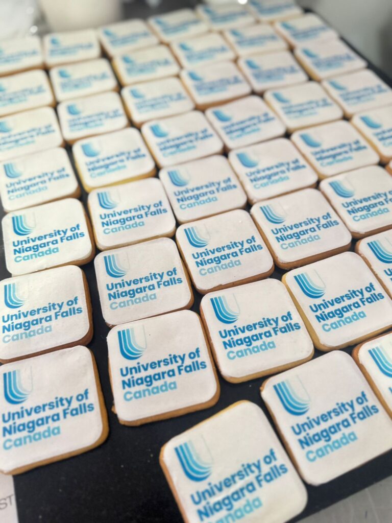 Galletas Personalizadas en Bogotá 15 "Galletas personalizadas con logo de la University of Niagara Falls Canada, diseño cuadrado ideal para eventos institucionales, ferias educativas y promoción universitaria, elaboradas en Bogotá."