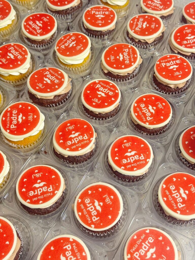 "Cupcakes corporativos personalizados para el Día del Padre con logo de empresa J&J, elaborados por Cake by Made en Bogotá. Decoración comestible con impresión personalizada en fondant y variedad de sabores."