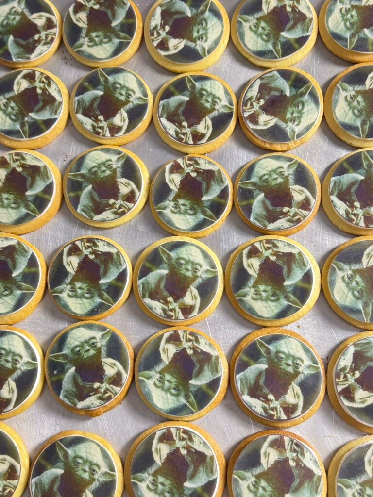 Galletas Personalizadas en Bogotá 24 Galletas artesanales personalizadas con imagen comestible del Maestro Yoda, perfectas para fiestas temáticas, regalos geek y branding creativo, elaboradas por Cake by Made Pastelería Saludable en Bogotá"
