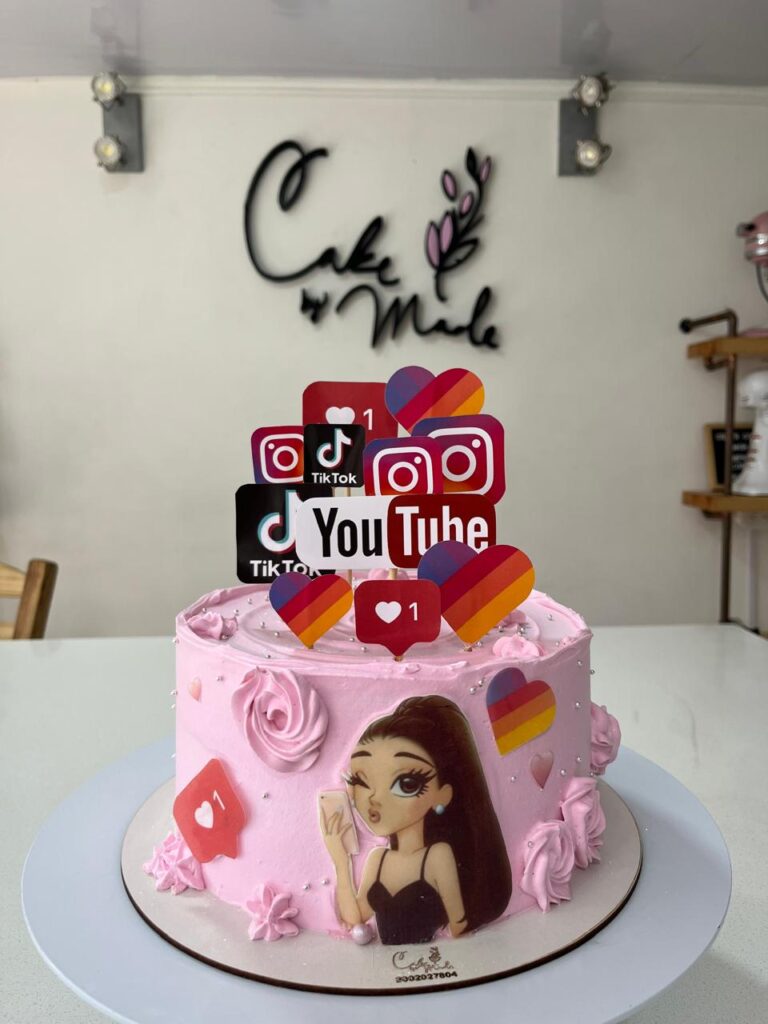 Tortas Personalizadas en Bogotá 52 "Torta personalizada rosa con temática de redes sociales como TikTok, YouTube e Instagram, decorada con topper de íconos digitales, corazones y una ilustración de chica influencer. Pastel artesanal para cumpleaños adolescentes o amantes del contenido digital, elaborado por Cake by Made en Bogotá